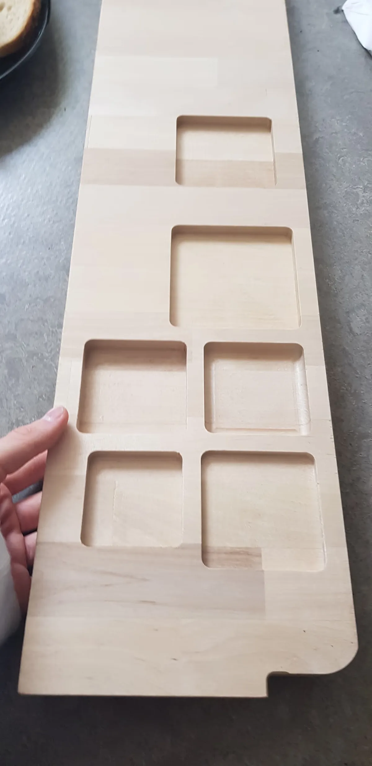 A photo of a wooden board with CNC'd holes in it to test the box sizes.