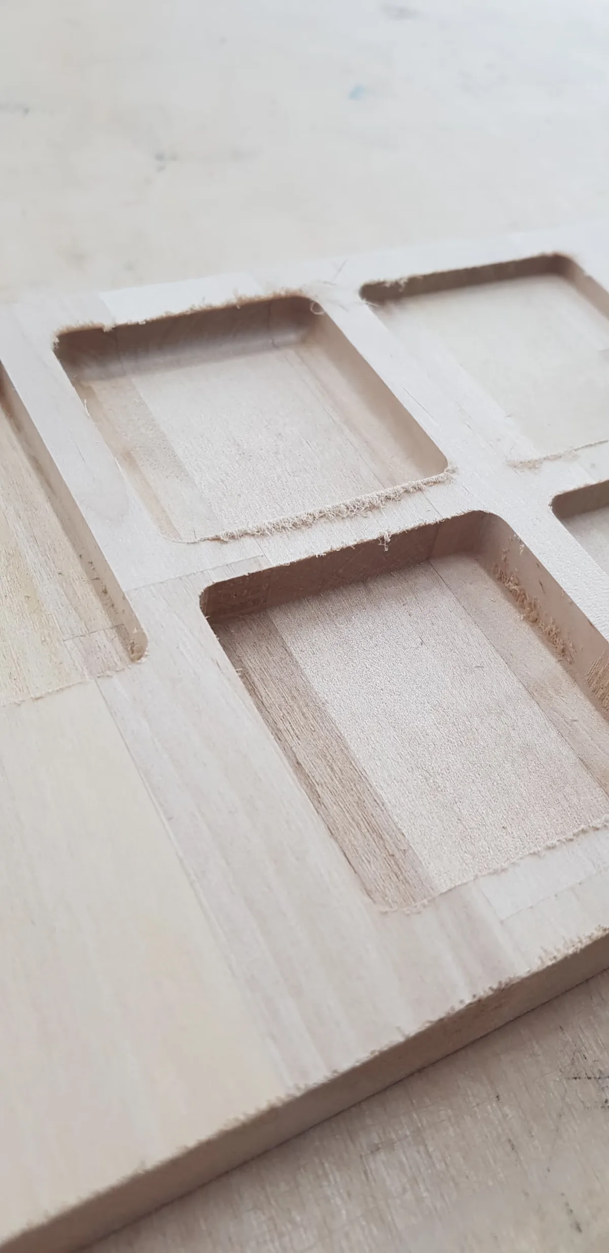 A photo of a wooden board with CNC'd holes in it to test the box sizes.